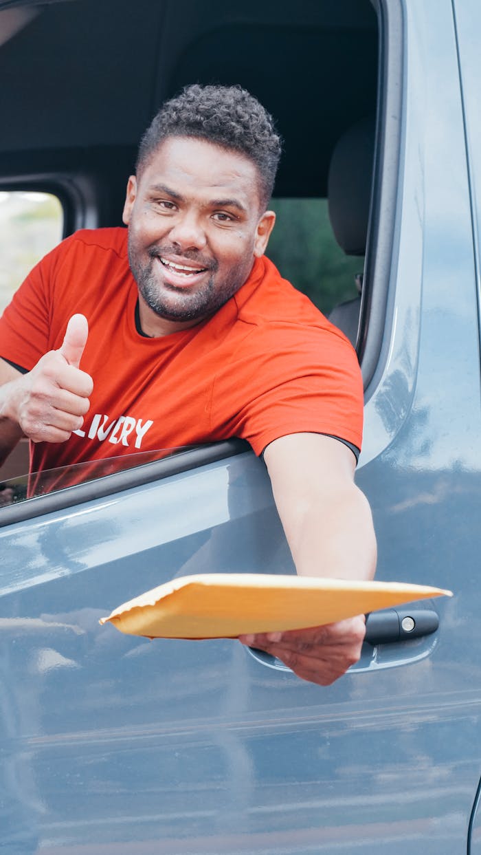 Services Smiling delivery man handing out a package from a van window, showcasing friendly service.
