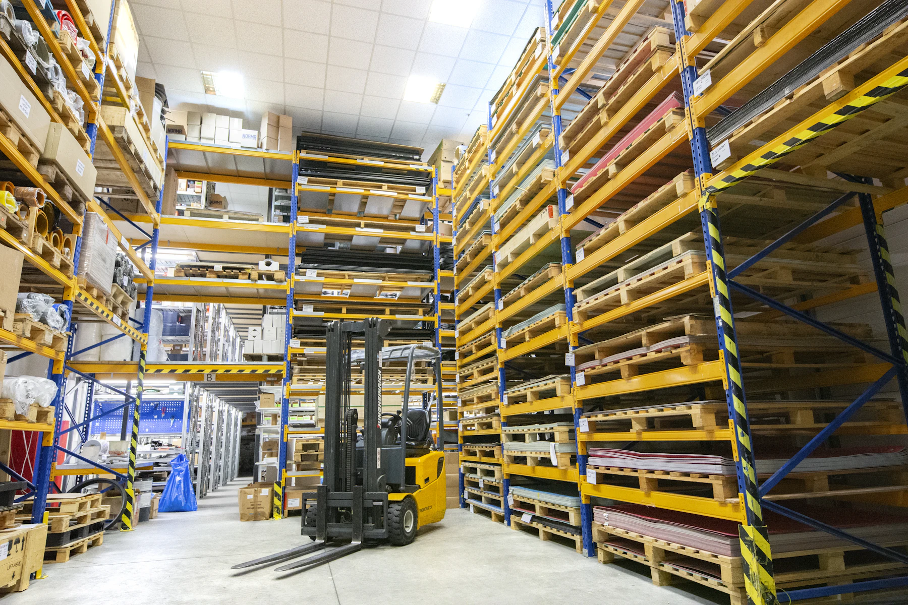 Large warehouse with rows of stacked pallets and steel racking