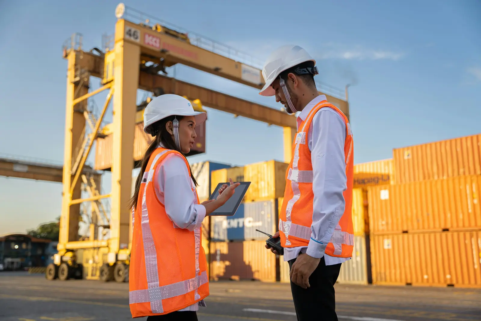Home Two logistics workers discussing cargo beside shipping containers