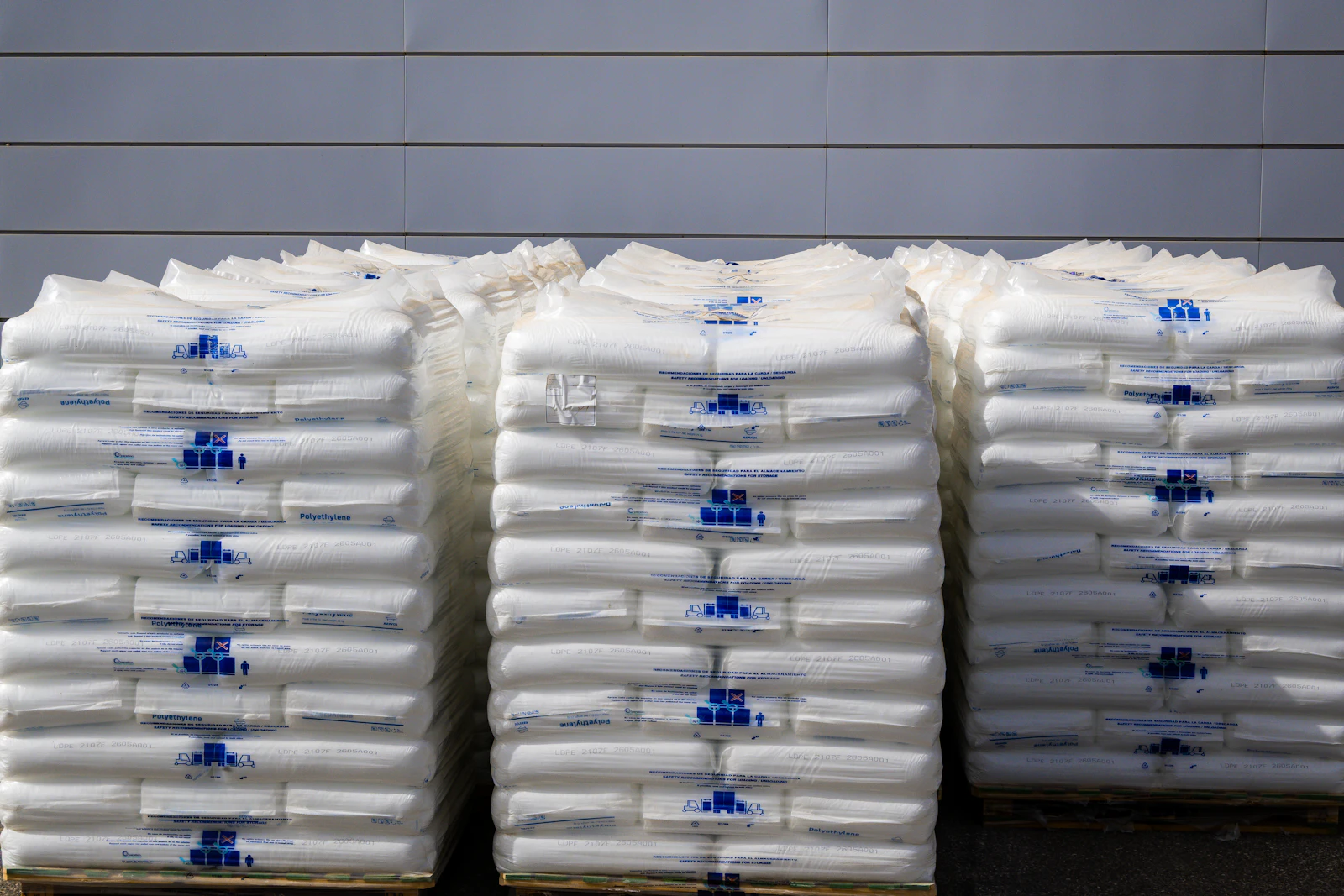 Three palletised stacks of white labelled sacks lined up ready for despatch
