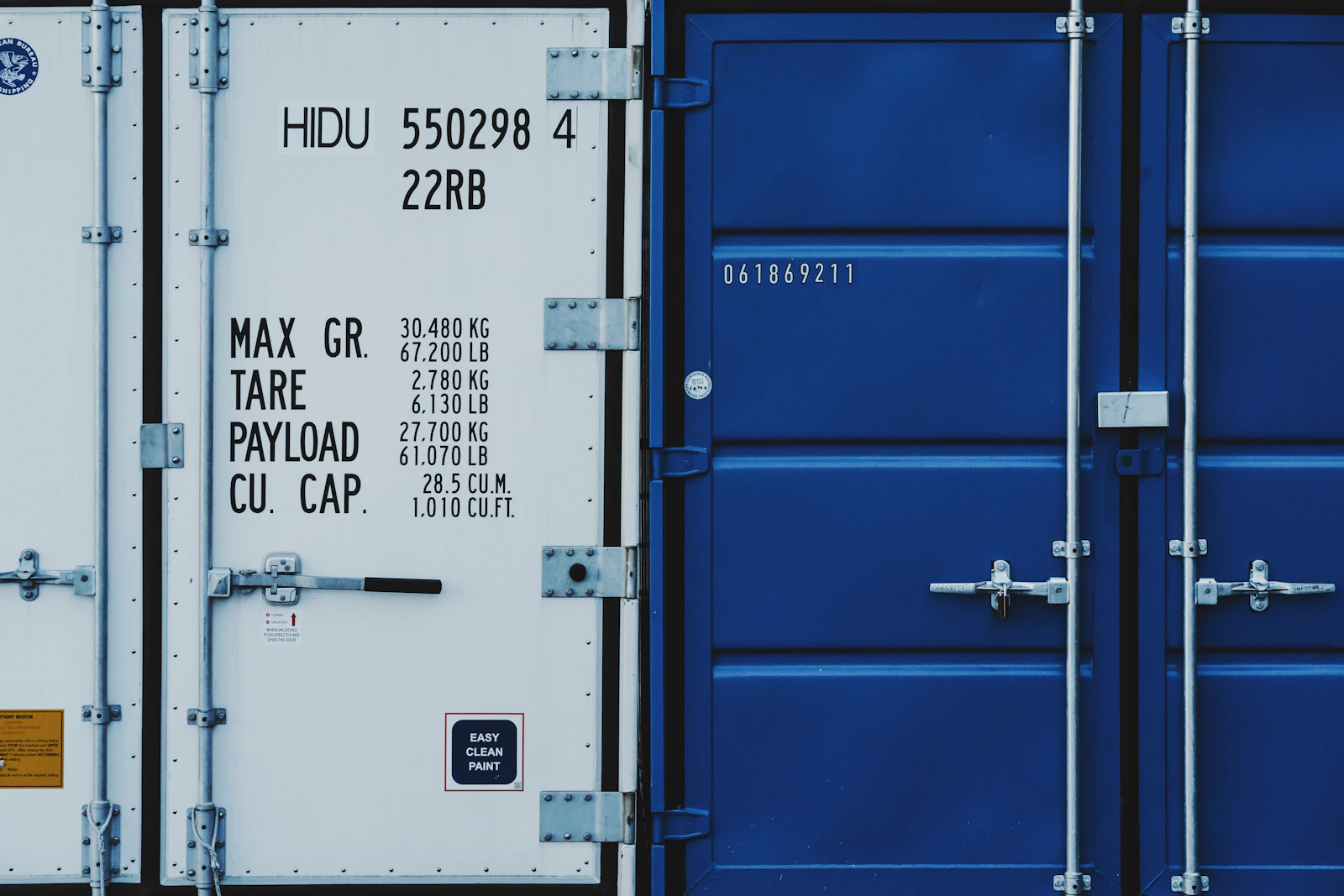 Two blue and white freight containers standing side by side outdoors