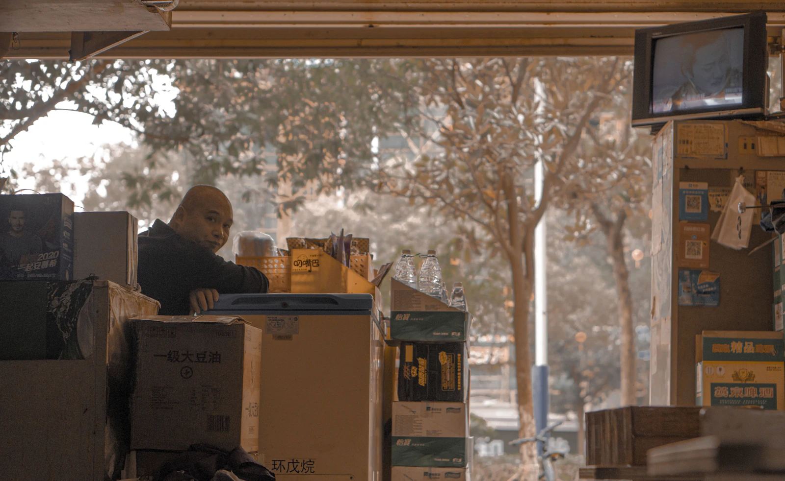 বাংলাদেশে কার্গো পাঠান — East End Logistics (বাংলা) Man sitting on the floor beside stacked brown cardboard packing boxes